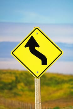 Closeup of a curvy road ahead sign.