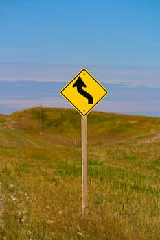 A curve ahead warning sign in the country.