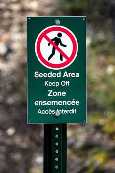 A seeded area keep off sign in french and english.