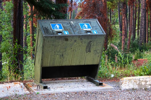 a bear proof garbage container along side a parking lot.