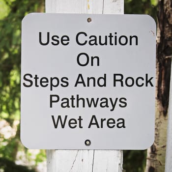 A use caution on steps and rock pathways sign.
