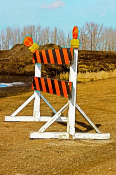 A construction barricade on a gravel road.