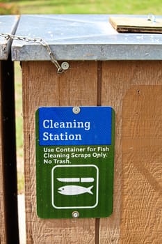 A cleaning station sign indicating container only for fish scraps.