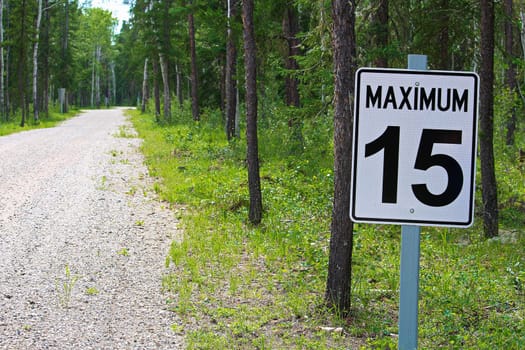 A maximum 15 speed limit sign along a gravel road.