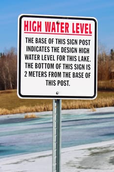 High water level sign along a storm drainage pond.