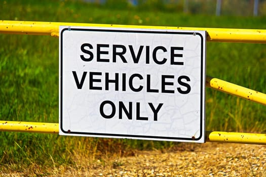 A service vehicles only sign on a metal gate.