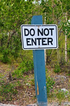 A do not enter sign with trees in the background.
