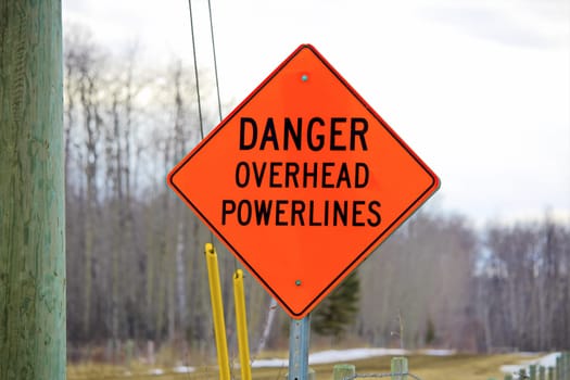 Danger overhead powerline sign beside a power pole.
