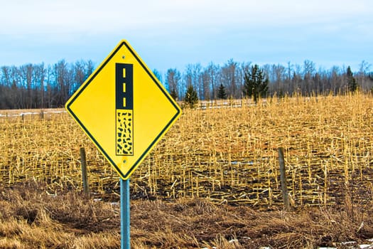 End of gravel road ahead warning sign.