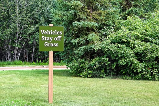 A green vehicles stay off the grass sign.