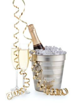 Still life with cooled champagne bottle standing in a bucket with ice, two full champagne flutes and gold streamer isolated on a white background, Christmas and New Year celebration