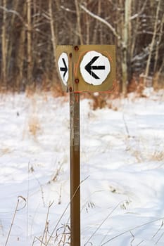 A white arrow direction sign along a hiking path.