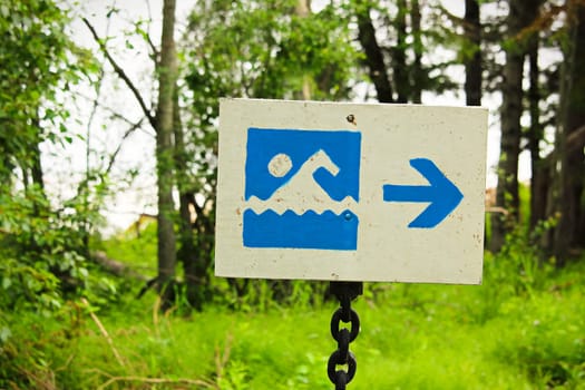 A blue beach beach sign with a direction arrow.