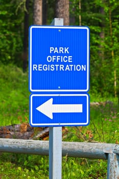 A blue park office registration direction sign.