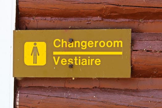 A female change room sign on painted red wood.