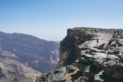 Grand Canyon of Oman. Tourist walking on the edge of cliff. Mountain range Jebel Akhdar.