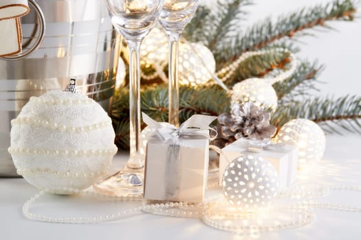 Still life with cooled champagne bottle standing in a bucket with ice, two champagne flutes and Christmas ornaments on a gray background, Christmas and New Year celebration