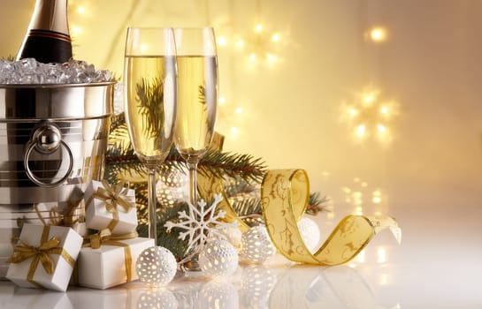 Still life with champagne bottle standing in a bucket with ice, two full champagne flutes, LED lights garland and Christmas ornaments. Christmas and New Year celebration background