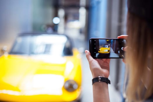 Hand holding phone mobile and takes pictures of a vintage car