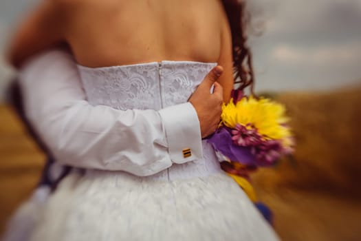 closeup of a groom's arm holding his bride's back