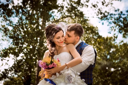 happy bride, groom standing in green park, smiling, laughing. lovers in wedding day.