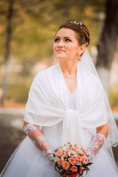 Beautiful bride in wedding dress and bridal bouquet, happy newlywed woman with wedding flowers, woman with wedding makeup and hairstyle. gorgeous young bride outdoors. Bride waiting for groom. bride