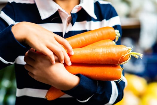 Young Person Carrying Armful of Fresh Organic Carrots Farmers Market Closeup Vegetables