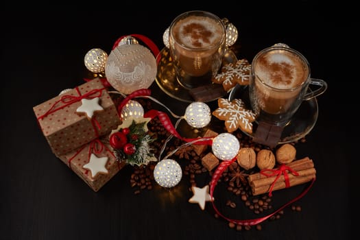 Still life with two cups of coffee, gingerbread cookies, gift box and Christmas decorations on a dark background with LED lights garland . Christmas and New Year treat. Top view