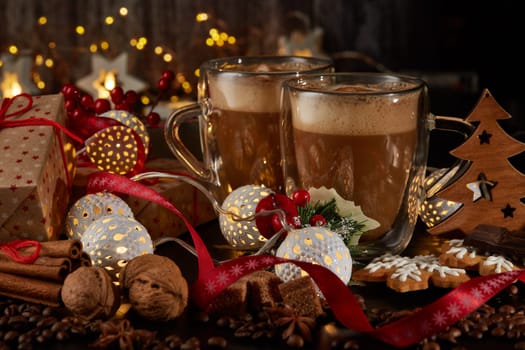 Still life with two cups of coffee, gingerbread cookies, gift box and Christmas decorations on a dark background with LED lights garland . Christmas and New Year treat.