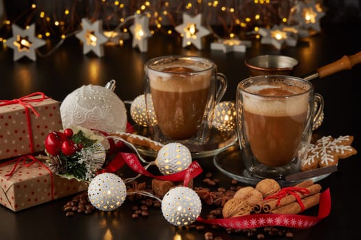 Still life with two cups of coffee, gingerbread cookies, gift box and Christmas decorations on a dark background with LED lights garland . Christmas and New Year treat.