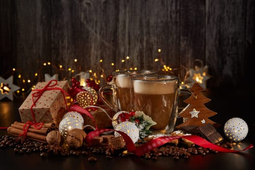 Still life with two cups of coffee, gingerbread cookies, gift box and Christmas decorations on a dark background with LED lights garland . Christmas and New Year treat.