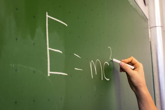 Female Hand Teacher Writing on Green Chalkboard Professor University White Chalk College Education Lesson E = mc2