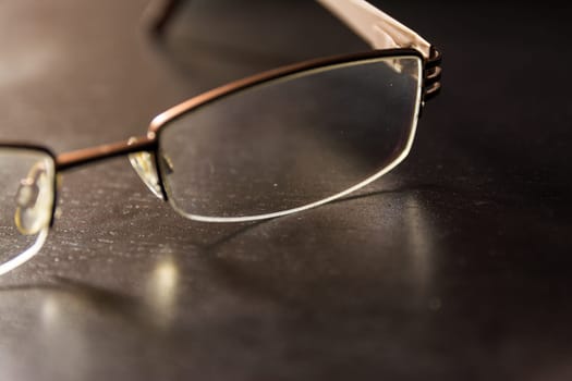 Brown Stylish Reading Glasses Setting on Black Desktop Workspace Empty Quiet
