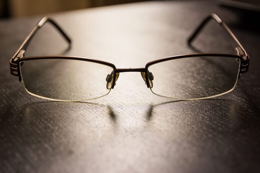 Brown Stylish Reading Glasses Setting on Black Desktop Workspace Empty Quiet