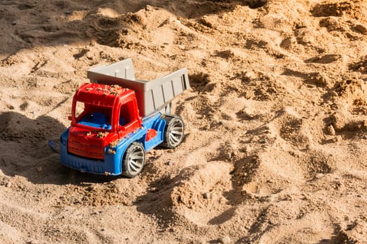Red Toy Truck Covered in Sand in Children Sandbox Playground