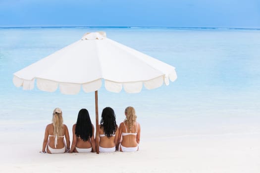 Happy young women in bikinis on summer beach
