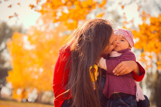 Mother kissing her daughter in the park