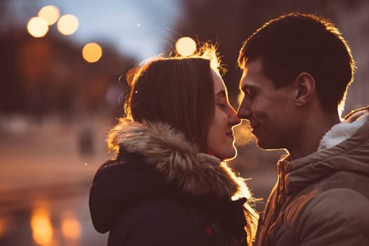 Portrait of young beautiful couple kissing in an autumn rainy day. Filtered with grain and light flashing
