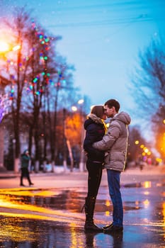 In love couple kissing in the snow at night city street. Filtered with grain and light flashing