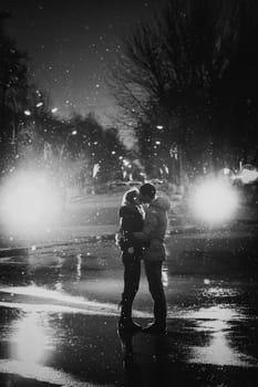 In love couple kissing in the snow at night city street black and white