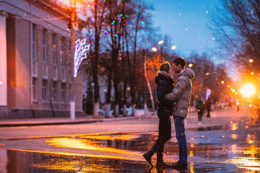 In love couple kissing in the snow at night city street. Filtered with grain and light flashing