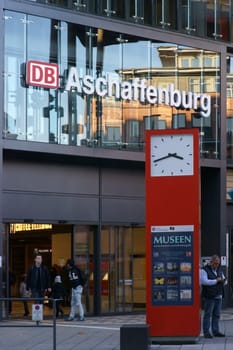 Aschaffenburg, Germany - November 17, 2018: Travelers stand in front of the modern glass facade and a grandfather clock of the Aschaffenburg central station on November 17, 2018 in Aschaffenburg...