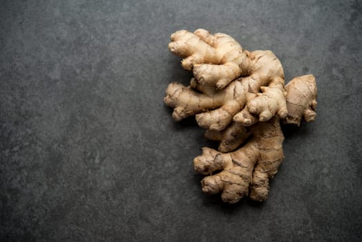 Top view fresh raw ginger root with copy space on dark background.