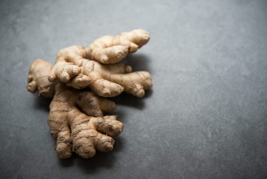 Fresh raw ginger root with copy space on dark background.