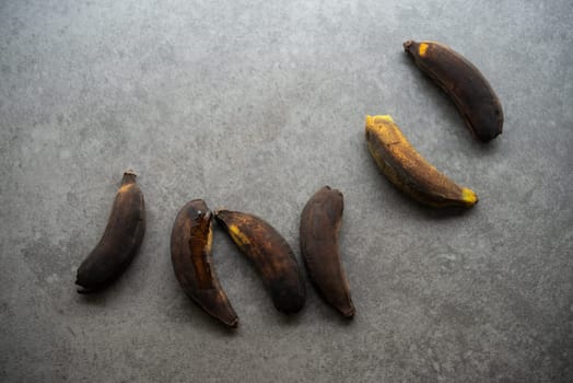 Rotten bananas on grey background.