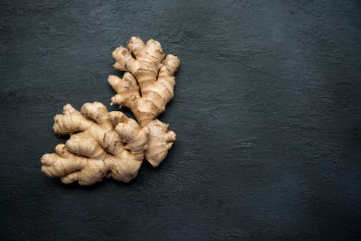Top view fresh raw ginger root with copy space on dark background.