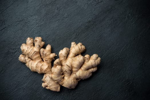 Top view fresh raw ginger root with copy space on dark background.