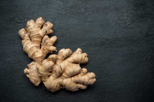 Top view fresh raw ginger root with copy space on dark background.