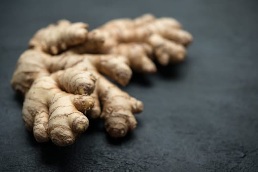 Fresh raw ginger root with copy space on dark background.