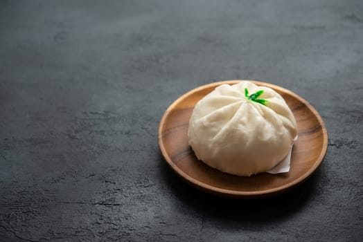 Baozi or bao dim sum on plate with copy space on dark background.